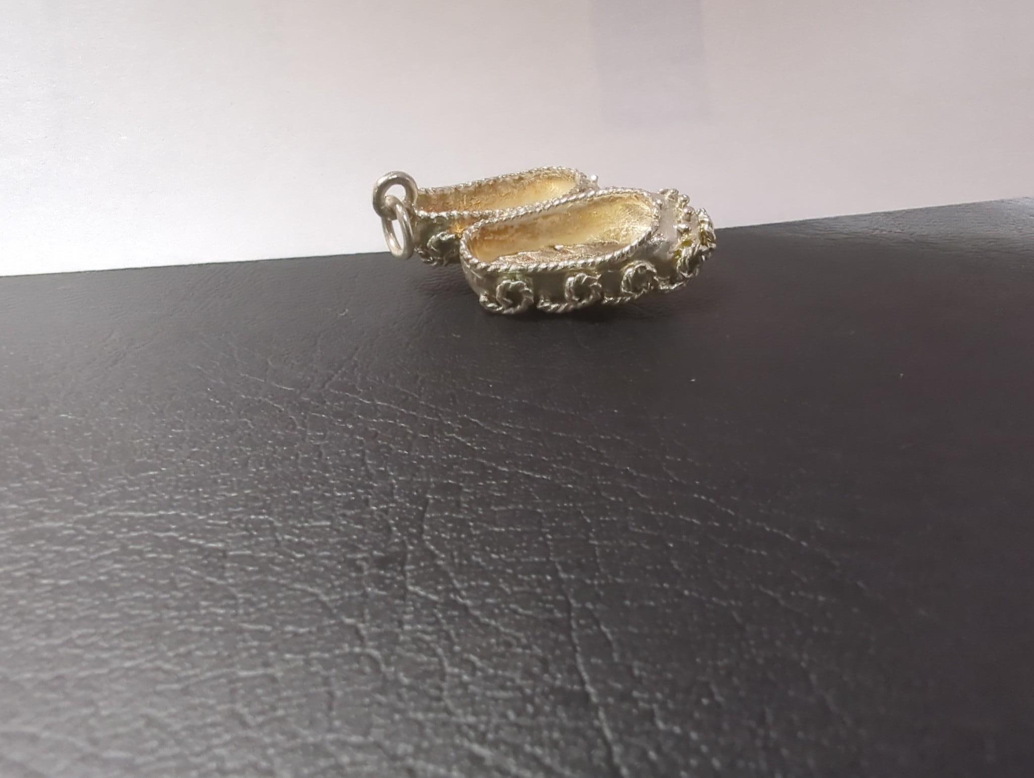 An Edwardian silver miniature model of an occasional chair, import marks for London, 1902, 43mm, a continental white metal model of a shoe and a similar model of a young child, a base metal 'book' box containing a rosary